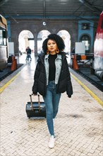 Young woman pulling suitcase in railway station