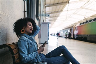Young woman holding smart phone on railway platform