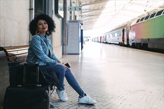 Young woman holding smart phone on railway platform