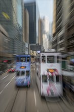 Blurred image of double-decker trams on street in Hong Kong, China