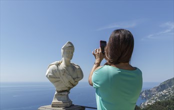 Woman taking photograph of sculpture bust