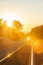 Railroad tracks bathed in sunlight during sunset