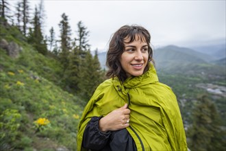 Young woman wearing green raincoat on hike