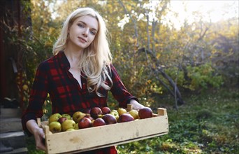 Young woman holding crate of apples
