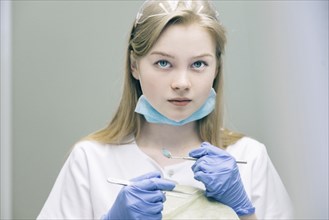 Portrait of young woman holding dentist equipment