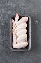 Raw chicken wings in roasting pan