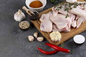 Raw chicken on cutting board with herb and spices