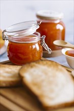 Jars of apricot jam by toast