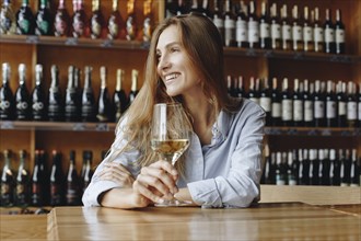 Smiling young woman holding glass of white wine