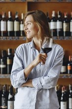 Smiling young woman holding glass of red wine
