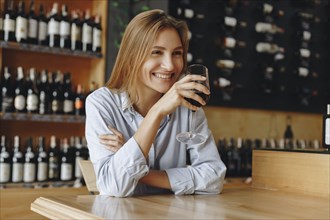 Smiling young woman holding glass of red wine