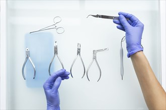 Hands of dental assistant wearing rubber gloves with dental equipment