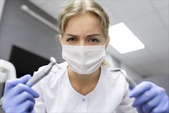 Patient point of view of dental assistant holding dental equipment