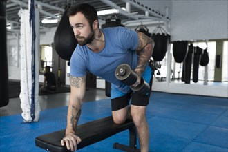 Mid adult man lifting dumbbell in gym