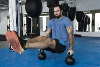Man balancing on kettlebells in gym