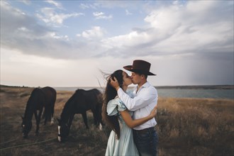 Young couple kissing in field by horses