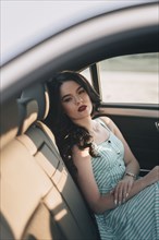 Young woman wearing striped dress sitting in car
