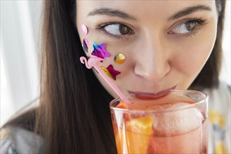 Woman with confetti on cheek drinking cocktail