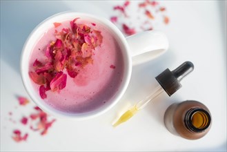 Pink drink topped with petals by pipette