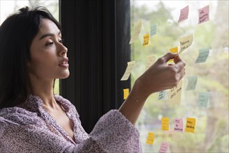 Businesswoman with adhesive notes on window