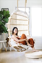Mid adult woman sitting on hanging chair