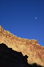 Moon over cliff in shadow in Capitol Reef National Park, USA