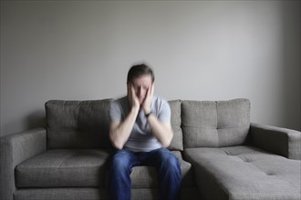 Depressed mature man sitting on couch