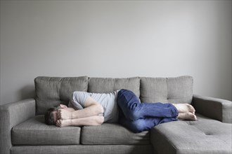 Depressed mature man lying on sofa