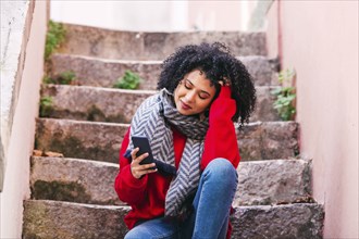 Young woman with smart phone sitting on steps