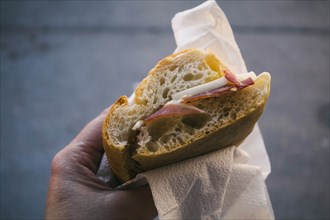 Woman's hand holding pancetta and cheese sandwich