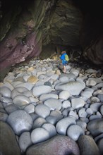 Teenage boy exploring cave with rocks in La Jolla, California
