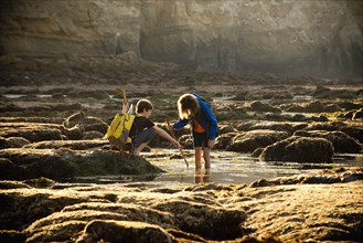 Teenage boys on rocks by tide pool in La Jolla, California