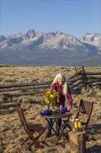 Mature woman setting dining table in field by mountain in Stanley, Idaho