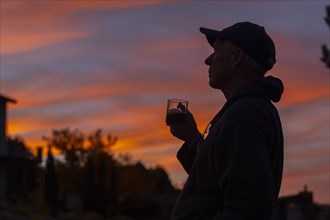 Silhouette of man holding coffee cup at sunset