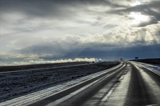 Country road with snow under overcast sky