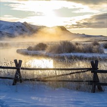 Fence by river at sunrise in Picabo, Idaho