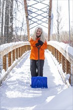 Mature woman holding shovel on snow covered footbridge