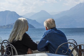 Gray haired couple sitting by Lake Como in Lombardy, Italy