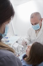 Dentist and hygienist cleaning patient's teeth