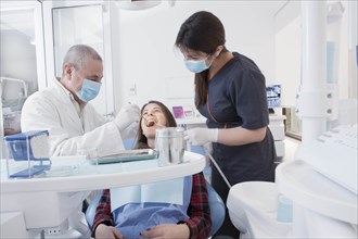 Dentist and hygienist cleaning patient's teeth