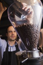 Barista pouring coffee beans into grinder
