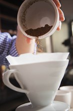 Barista pouring coffee grounds into filter