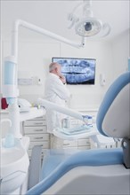 Dentist examining X-ray on television screen