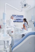 Dentist and dental hygienist examining X-ray on television screen
