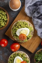 Avocado with egg and tomato on rice cakes