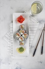 Plate of sushi with chopsticks and drinking glass