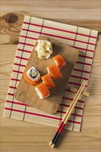 Salmon sushi on cutting board with chopsticks and mat