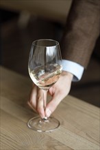 Hands of man swirling glass of white wine