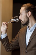 Young man smelling wine in glass at tasting
