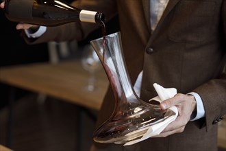 Waiter pouring red wine into decanter